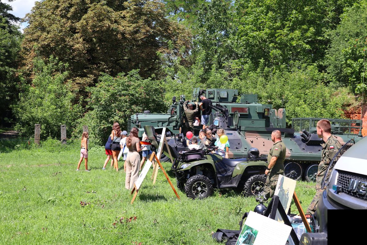 ustawione obok siebie pojazdy wojskowe koloru zielonego wokół spacerują zwiedzający. Przy pojazdach stoją umundurowani żołnierze