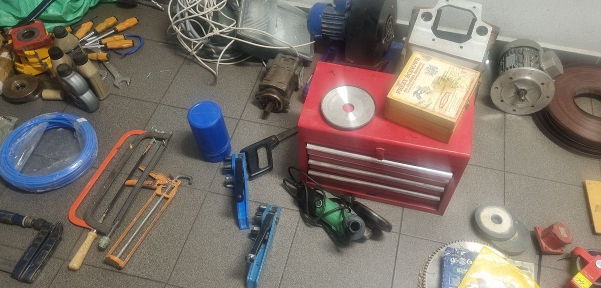 Skradzione przedmioty w postaci narzędzi specjalistycznych, elektro narzędzi oraz narzędzi warsztatowych ułożone obok siebie na podłożu..