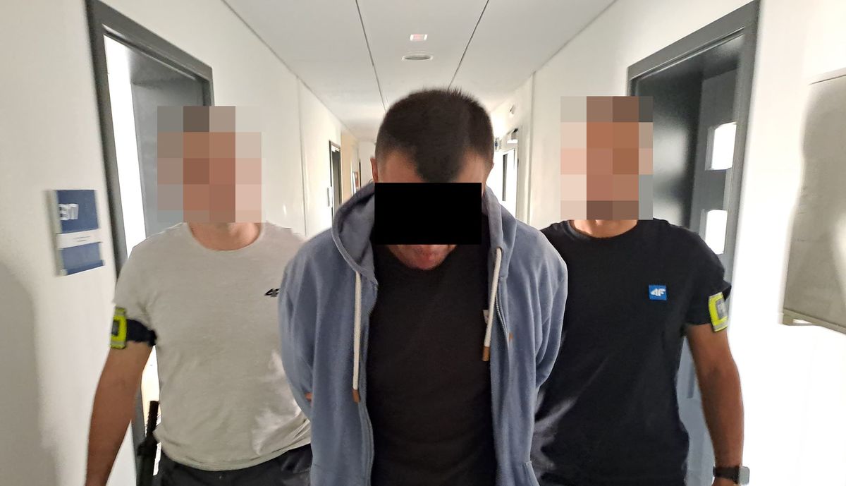 Policjanci prowadzą zatrzymanego mężczyznę.
