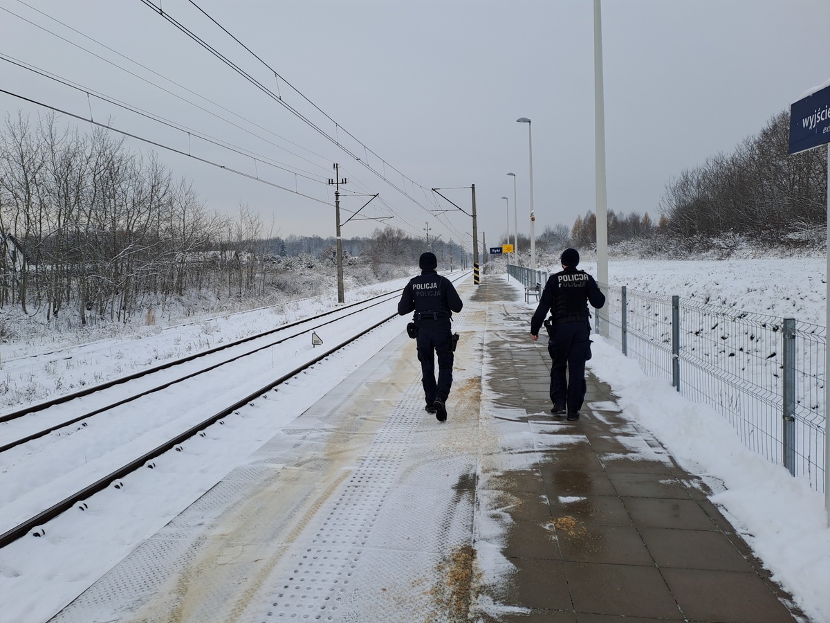 Funkcjonariusze policji  patrolują i sprawdzają teren linii kolejowej.