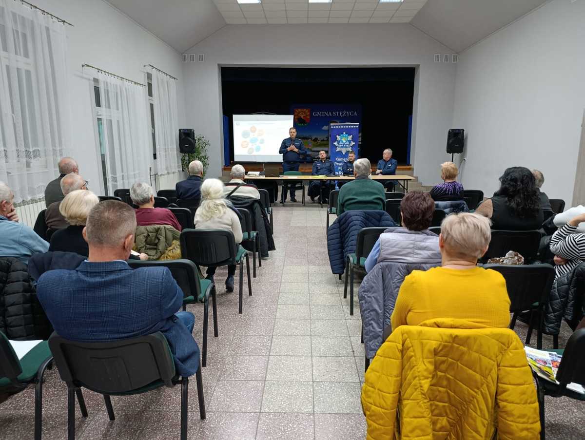 Uczestnicy debaty na sali konferencyjnej GOK w Stężycy siedzą na krzesłach policjant przemawia