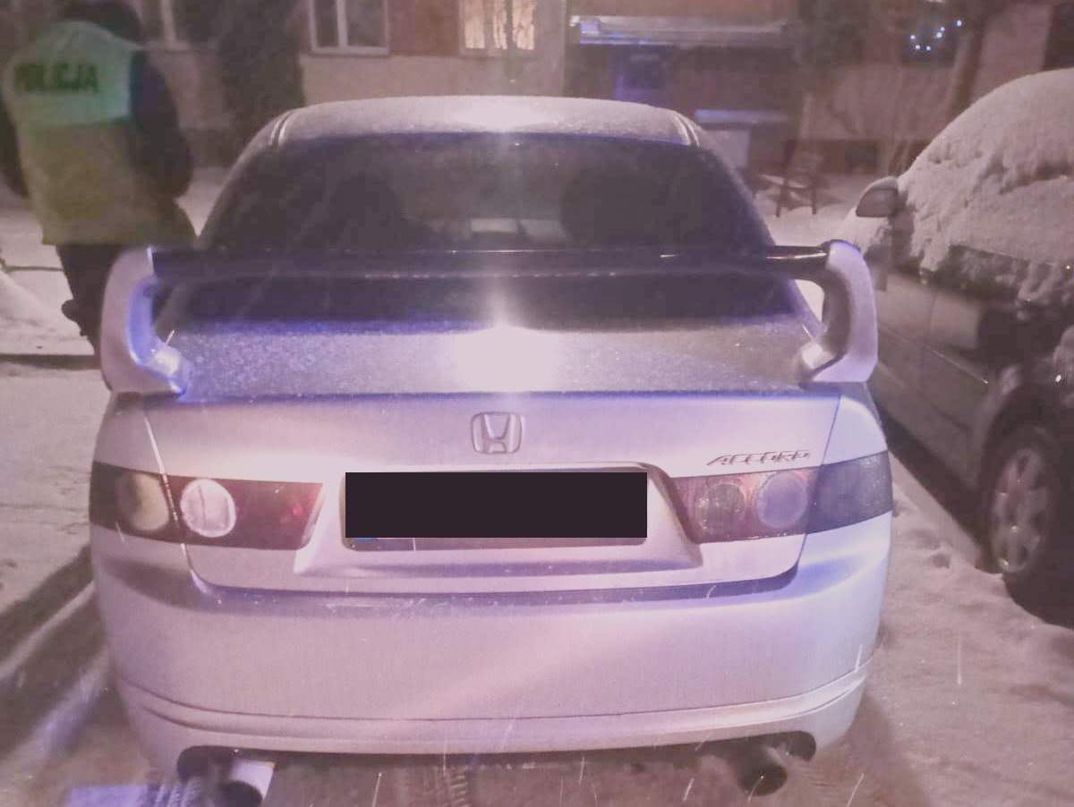 Samochód osobowy koloru srebrnego zatrzymany do kontroli obok stoi policjant