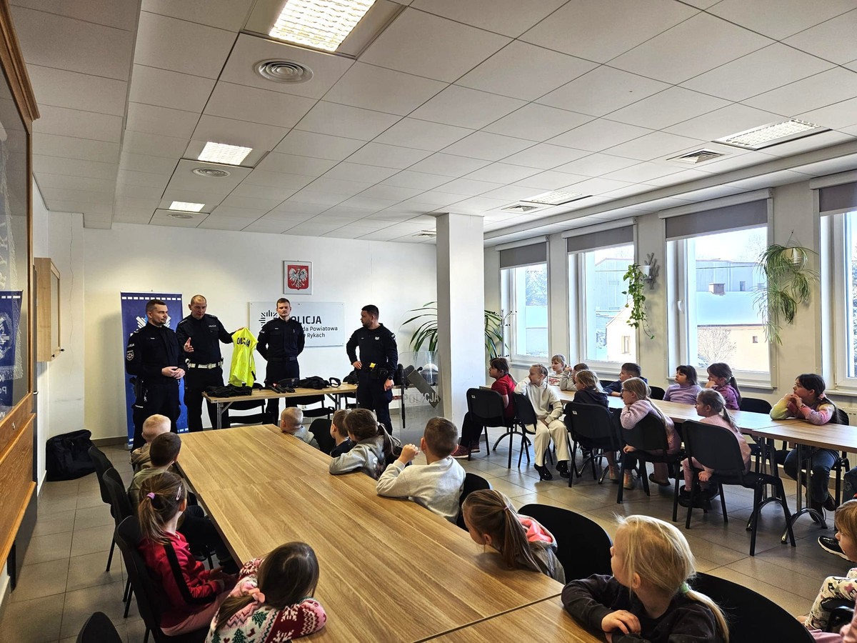 Dzieci podczas prelekcji policjantów siedzą przy stołach w sali odpraw