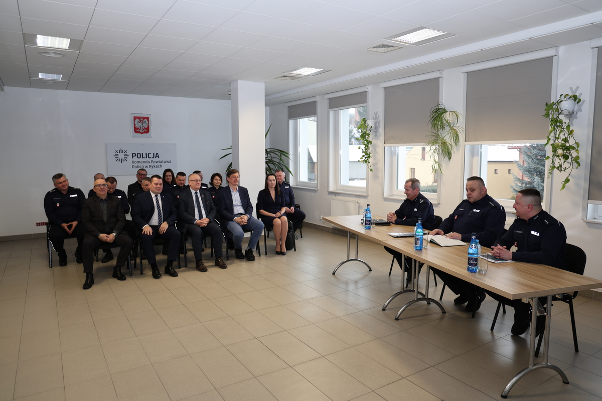 uczestnicy odprawy służbowej siedzący w sali odpraw