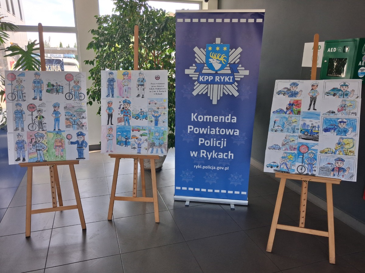 prace dzieci na sztalugach oraz rolap z logiem Komedny Policji w Rykach