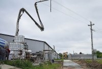 samochód typu betoniarka z rozłożonym masztem do przepompowywania betonu na tle hali i linii elektrycznej