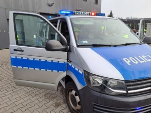 Zdjęcie przedstawia grupę dzieci ze szkoły podstawowej nr 2 w Dęblinie ubrane w różne kolorowe ubrania, Dzieci zwiedzają obiekt Komendy Powiatowej Policji w Rykach i zapoznają się ze sprzętem wykorzystywanym w słuzbie.