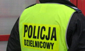 Policjant umundurowany odwrócony plecami z kamizelką odblaskową z napisem |Policja dzielnicowy