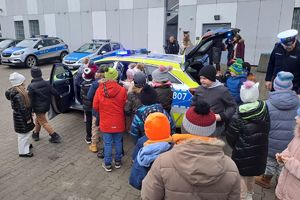 Zdjęcie przedstawiają uczniów,  i nauczycieli szkoły podstawowej w Nowej Rokitni podczas zwiedzania Komendy Powiatowej Policji w Rykach. Dzieci oglądają radiowóz oznakowany.