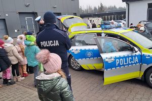 Zdjęcie przedstawiają uczniów,  i nauczycieli szkoły podstawowej w Nowej Rokitni podczas zwiedzania Komendy Powiatowej Policji w Rykach. Dzieci oglądają radiowóz oznakowany,