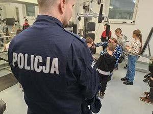 Zdjęcie przedstawiają uczniów,  i nauczycieli szkoły podstawowej w Nowej Rokitni podczas zwiedzania Komendy Powiatowej Policji w Rykach. Dzieci zwiedzają siłownię i ćwiczą