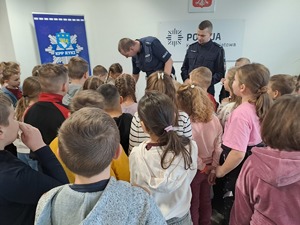 Zdjęcie przedstawiają uczniów,  i nauczycieli szkoły podstawowej w Nowej Rokitni podczas zwiedzania Komendy Powiatowej Policji w Rykach.