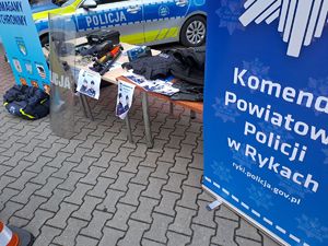 Stoisko Komendy Powiatowej Policji w Rykach na finale w WOSP w Rykach na placu OSP przy kinie Renesans. Widoczne pojazdy służbowe radiowozy oznakowane i nieoznakowane i sprzęt policyjny.