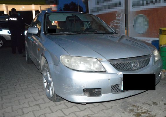 Samochód osobowy koloru srebrnego marki mazda zaparkowany na parkingu z widocznymi uszkodzeniami