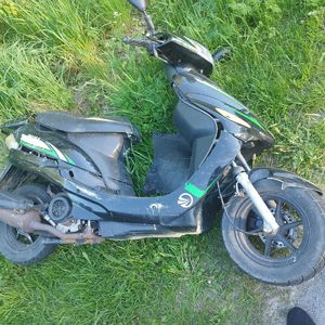 Motorower uszkodzony leżący poza jezdnia na trawie.