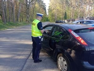 Policjant umundurowany dokonuje kontroli stanu trzeźwości kierującego samochodem osobowym na poboczu drogi