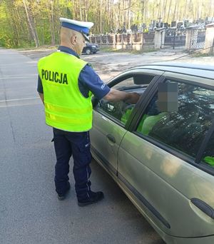 Policjant umundurowany dokonuje kontroli stanu trzeźwości kierującego samochodem osobowym na poboczu drogi