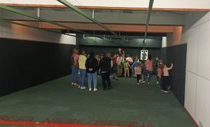 Grupa kilkunastu dzieci i policjant podczas zwiedzania strzelnicy w  budynku Komendy Powiatowej Policji w Rykach