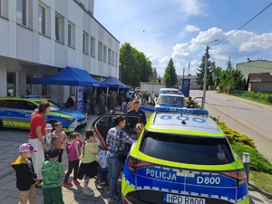 Zdjęcie stoiska policji ustawione przed budynkiem komendy policji w Rykach. Przy stoisku są odwiedzający oraz stoją pojazdy policyjne.