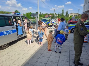 Zdjęcie stoiska policji ustawione przed budynkiem komendy policji w Rykach. Przy stoisku są odwiedzający oraz stoją pojazdy policyjne.