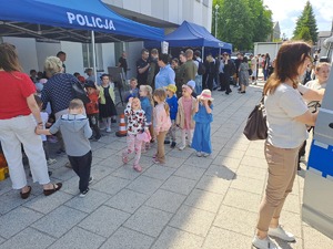 Zdjęcie stoiska policji ustawione przed budynkiem komendy policji w Rykach. Przy stoisku są odwiedzający oraz stoją pojazdy policyjne.