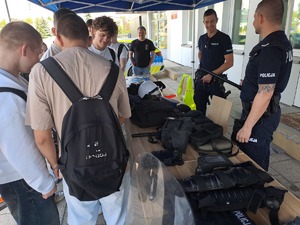 Zdjęcie stoiska policji ustawione przed budynkiem komendy policji w Rykach. Przy stoisku są odwiedzający