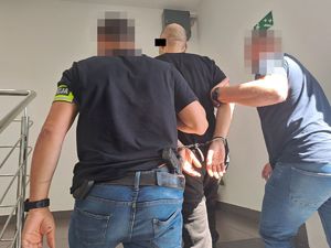 Policjanci prowadzą zatrzymanego mężczyznę.