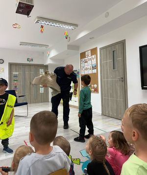 fotografia ze spotkani policjantów z przedszkolakami. Policjant prezentuje wyposażenie policjanta przedszkolak.