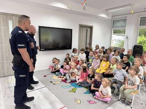 fotografia ze spotkani policjantów z przedszkolakami. Policjanci stoją przed grupa dzieci