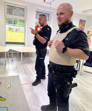 fotografia ze spotkani policjantów z przedszkolakami. Policjanci stoją i prezentują wyposazenie