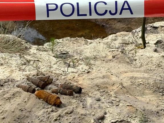 Niewybuchy z czasów II wojny Światowej leżące na piachu ogrodzone taśmą z napisem Policja.