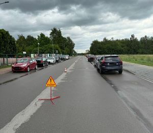 Zdjęcia ze zdarzenia drogowego wzdłuż drogi stają zaparkowane pojazdy na środku jezdni  są ustawione pachołki