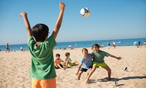 Grupa dzieci gra w piłkę na plaży.