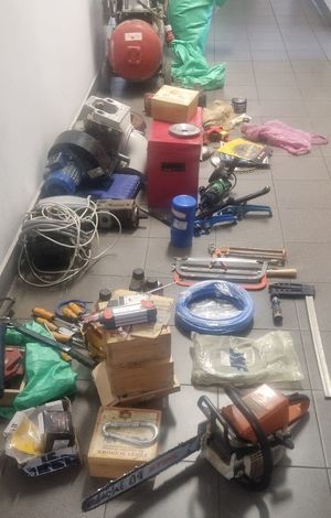 Skradzione przedmioty w postaci narzędzi specjalistycznych, elektro narzędzi oraz narzędzi warsztatowych ułożone obok siebie na podłozu..