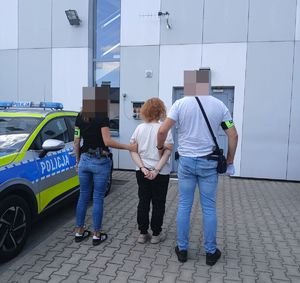 Zatrzymana kobieta prowadzona przez nie umundurowanych policjantów