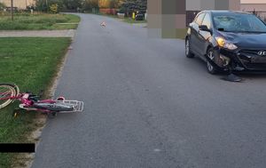 Miejsce zdarzenia drogowego z lewej strony stoi uszkodzony damo chód osobowy Hyundai a po prawej stronie na poboczu leży rower koloru różowego.