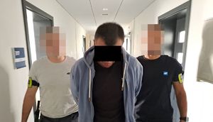 Policjanci prowadzą zatrzymanego mężczyznę.