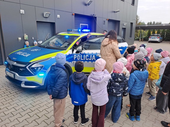 Grupa przedszkolaków zwiedza obiekt Komendy Powiatowej Policji w Rykach i zapoznaje się ze sprzętem