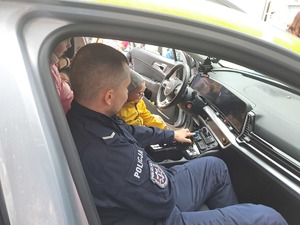 Grupa przedszkolaków zwiedza obiekt Komendy Powiatowej Policji w Rykach i zapoznaje się ze sprzętem
