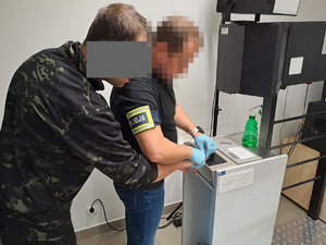 Policjant pobiera odbitki palców na urządzeniu elektronicznym od zatrzymanego meżczyzny