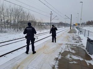 Funkcjonariusze policji  patrolują i sprawdzają teren linii kolejowej.