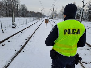 Funkcjonariusze policji  patrolują i sprawdzają teren linii kolejowej.