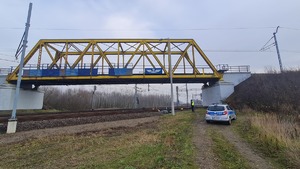 Funkcjonariusze policji  patrolują i sprawdzają teren linii kolejowej.