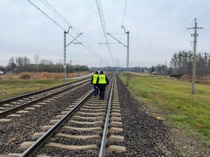 Funkcjonariusze policji i straży ochrony kolei patrolują i sprawdzają teren linii kolejowej.