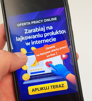 telefon trzymany w dłoni z wyświetlana grafika z ogłoszeniem i ostrzeżeniem o fałszywych ofertach pracy on-line