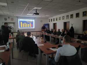 Uczestnicy debaty siedzący na krzesłach w sali konferencyjnej