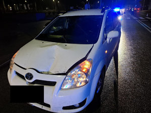 Zdjęcia z miejsca wypadku drogowego., Widoczna jest droga na której stoi uszkodzony  biały samochód osobowy.