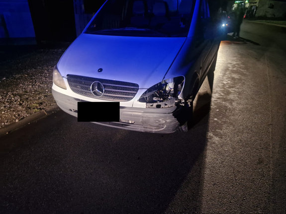 Pojazd osobowy z uszkodzonymi przodem w wyniku zdarzenia drogowego. Pojazd stoi na drodze asfaltowej. Zdjęcie  w porze nocnej.