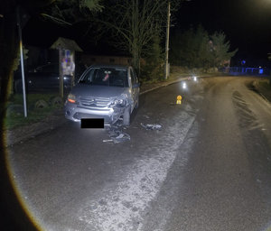 Pojazd osobowy z uszkodzonymi przodem w wyniku zdarzenia drogowego. Pojazd stoi na drodze asfaltowej. Zdjęcie w porze nocnej.