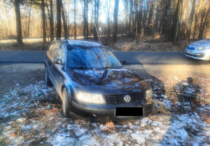 Samochód marki Volkswagen koloru granatowego stojący w rowie przydrożnym obok radiowóz policji